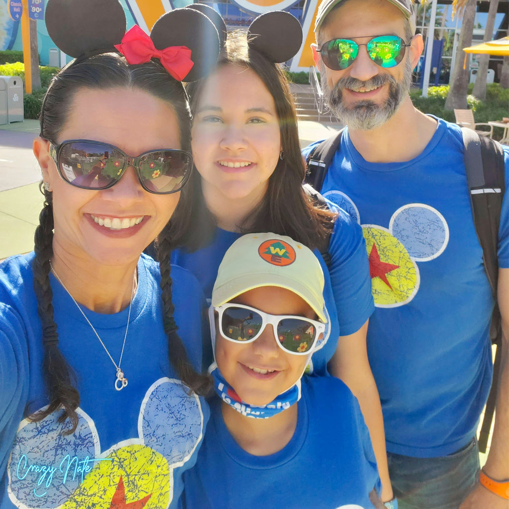 Family of four wearing matching blue shirts with cartoon character designs, posing outdoors.