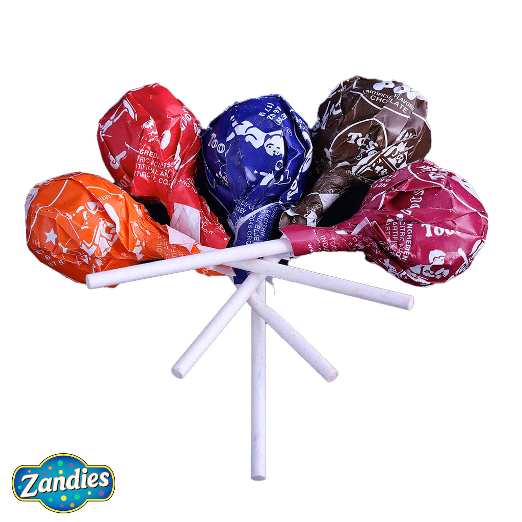 Small pile of Tootsie Roll Lollipops. One of each color. Orange, red, blue, brown, and dark red. One of the wrappers has the Indian with a star. Zandies logo in the corner.