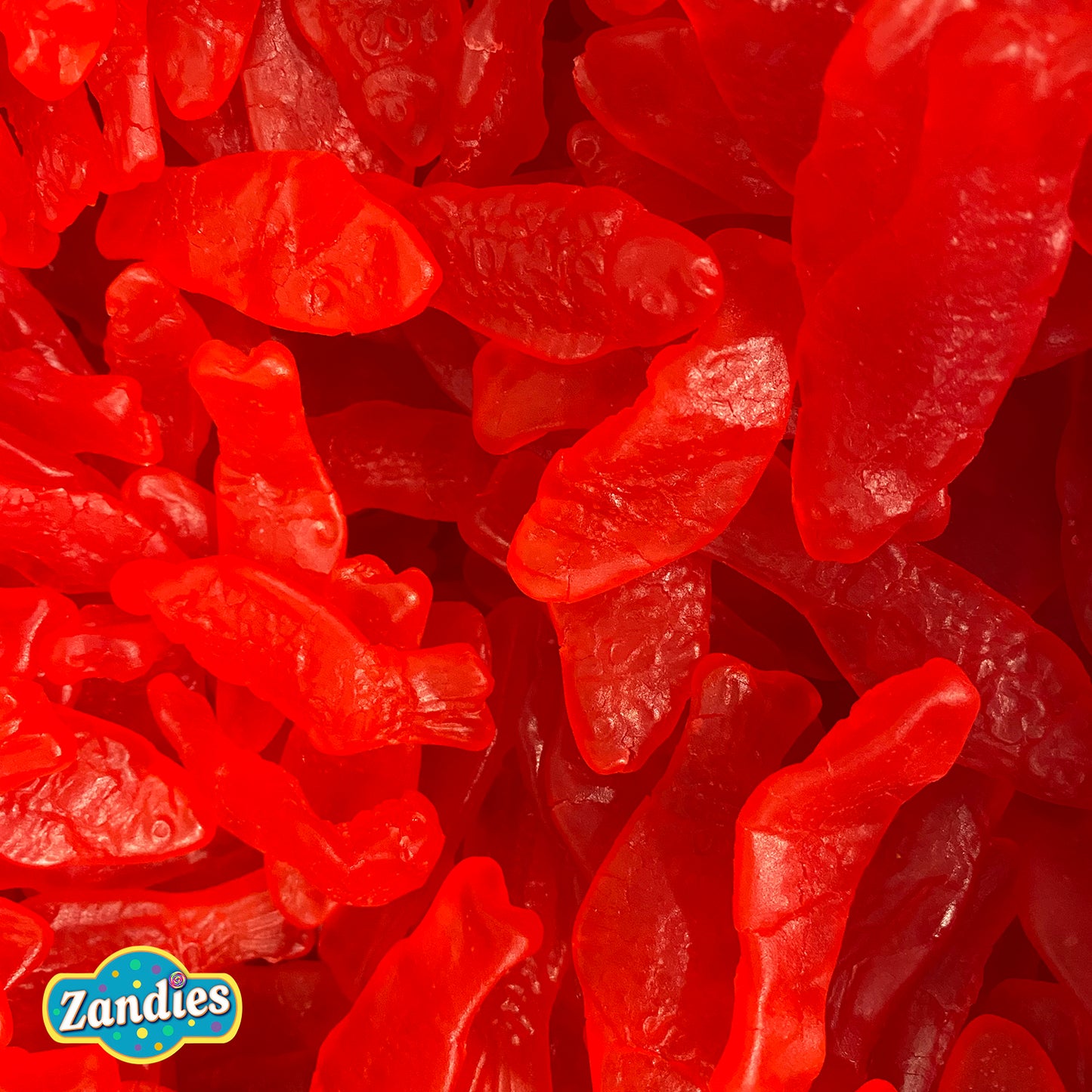 Large pile of chewy red Swedish Fish gummy candies stacked together for snacking or bulk sale